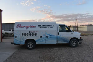 White Champion Plumbing, Heating & Air service van with blue water graphics parked on gravel under a cloudy sky.